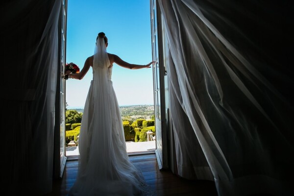 This picture it´s part of Judith and Greig Destination Wedding in Portugal. At the moment we were taking pictures of the bride in the living room of the Seteais Hotel, where she got ready. I ask the bride, just before living for the ceremony, as we were in hurry, one last photo catching the amazing garden and view. As she open the doors a strong wind enter in the room and I only had time to take 3 pictures before living, as the bride looked to the horizon and left in the hurry to meet her husband to be!! So, besides I asked the bride to open the doors, this is a very natural and candid photo, because I didn´t asked for anything else, I only appreciate the way the curtains moved as she looked to the horizon and looked for the best point of view.