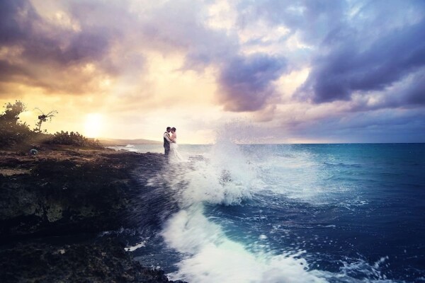 Towards the end of the day when the sun was setting in beautiful Negril, Jamaica, the bride and groom and I headed down to the ocean near some cliffs to take some photos. The waves were violently crashing up against the cliffs surrounding a small cove and I decided to have the bride and groom stand on one cliff as I made my way to another cliff across from them to get the entire scene on camera. We waited a long time to get this shot, as I was perched on the very edge of the cliff to gain a different perspective and went through getting soaked a couple of times by waves before getting this image! I knew the second that I took this shot, it would be my favorite and it really is! It's everything about the warmth, beauty and excitement of being in Jamaica! Needless to say, I am soo lucky to have clients who were willing to literally put themselves on the edge of a cliff with waves crashing up on them on their wedding day. It was just such an amazing way to end the day.