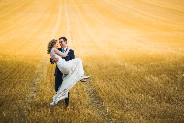 Nikki & Ed got hitched just as summer was turning to autumn. The trees were beginning to shed their leaves and the fields, once golden and swaying with corn were now cut down completely. I saw this epic backdrop, a rolling hill which went on for as far as the eye could see - and knew instinctively it would be a beautiful place to frame my couple for a portrait shoot. On the way back in Nikki's dress was getting tangled in the corn stalks so Ed (being the true gent) picked her up. It's a legitimate beautiful moment and one I'm proud to have captured.