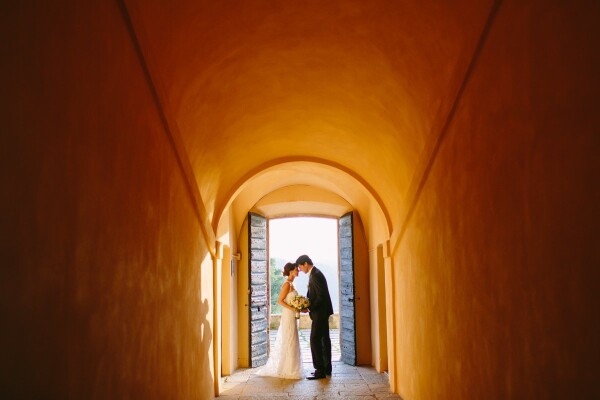 This photo was taken at Valentina & Daniel's wedding in an Italian castle located in Lake Maggiore, which was their wedding venue. As soon as we arrived, we were having a cocktail party just outside this door. As soon as I saw this amazing golden light I asked them to briefly stop in the middle of the doorframe and I took this photo. This is my favorite portrait from their wedding! Such gorgeous light & architecture! <br />
