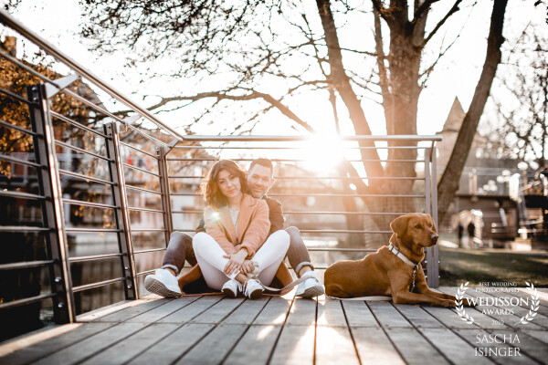 This is Stephanie, Julian, and Sam.<br />
We took this photo during our lovebird shooting in the old town of Nuremberg. Walking hand in hand down their hometown with the most important part of their life (the dog Sam) was a wish. <br />
We took the chance to get the sunset in the right spot with them. 