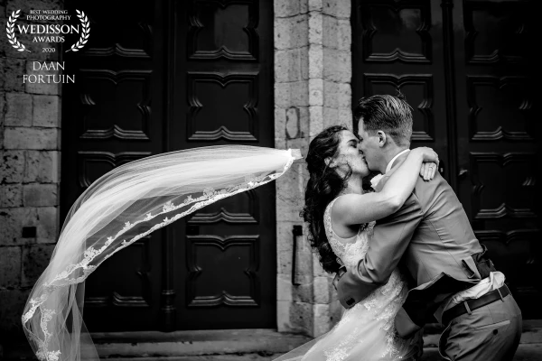 The wind was blowing so hard during the making of this photo. In a series of 3 photos, the bride lost her veil. Love this one the most During this photo, the bride had no idea that they had to sprint shortly after this kiss...