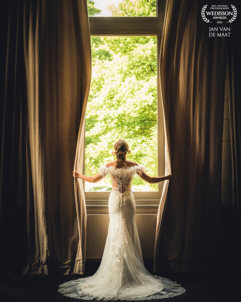 Large windows and long curtains always attracts my attention when I am on location. This time I was lucky I found one and placed the bride in front of it. The back of her dress was created beautifully with a lace design and I wanted an image that showed this. I asked her to move the curtains a bit and this is the result!