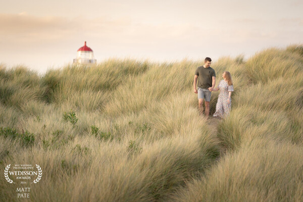 Emma & Rik enjoying a walk through the long grass on the sand dunes at sunset. I love the fact the very top of the lighthouse is just showing to at to the story of this image.