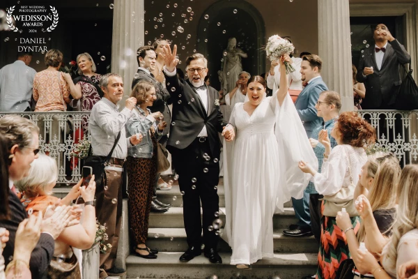 The bride and groom come out of the civil registry office and are greeted with cheers by the guests.