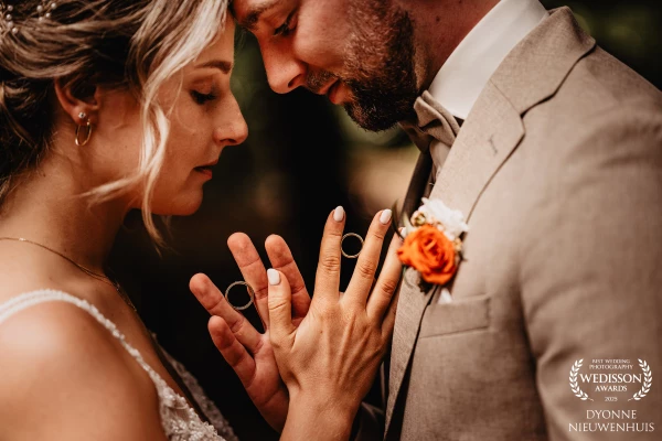 A tender moment as the couple touches hands, holding wedding rings with deep love.