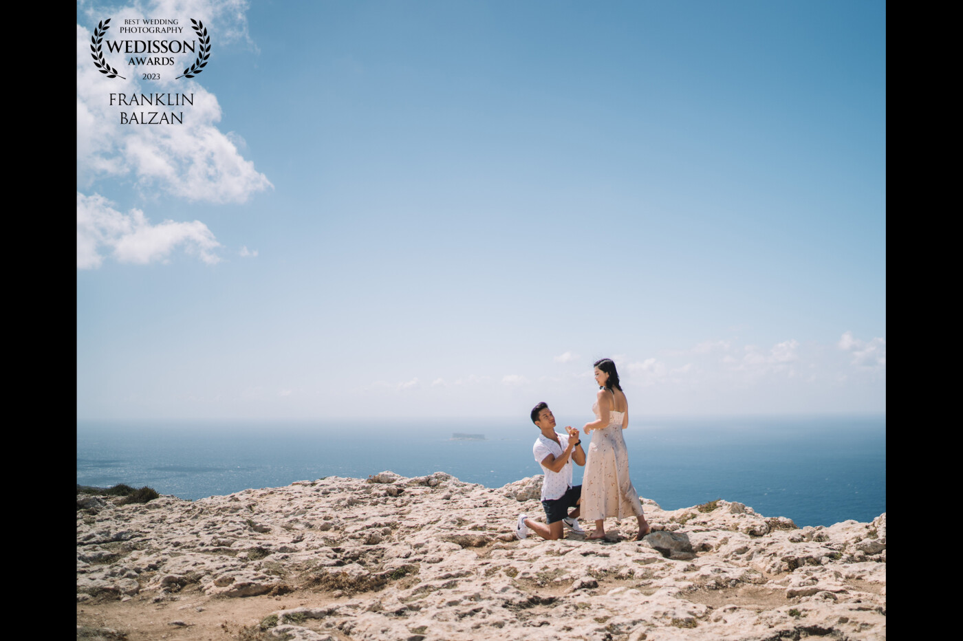 The proposal image is set against the stunning backdrop of Dingli Cliffs, which tower high above the crystal clear waters of the Mediterranean Sea. The couple stands at the edge of the cliffs,  framed against the breathtaking views of the ocean and the distant horizon.