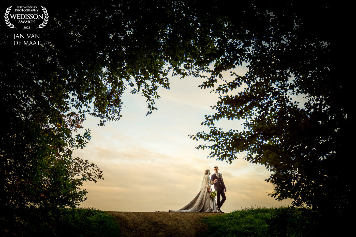 This photo was taken at the end of a tree lane. The lane was going upwards to a dike. The tree foliage was creating a beautiful frame. I placed the couple on the dike and let them walk a little and so could take this photo!