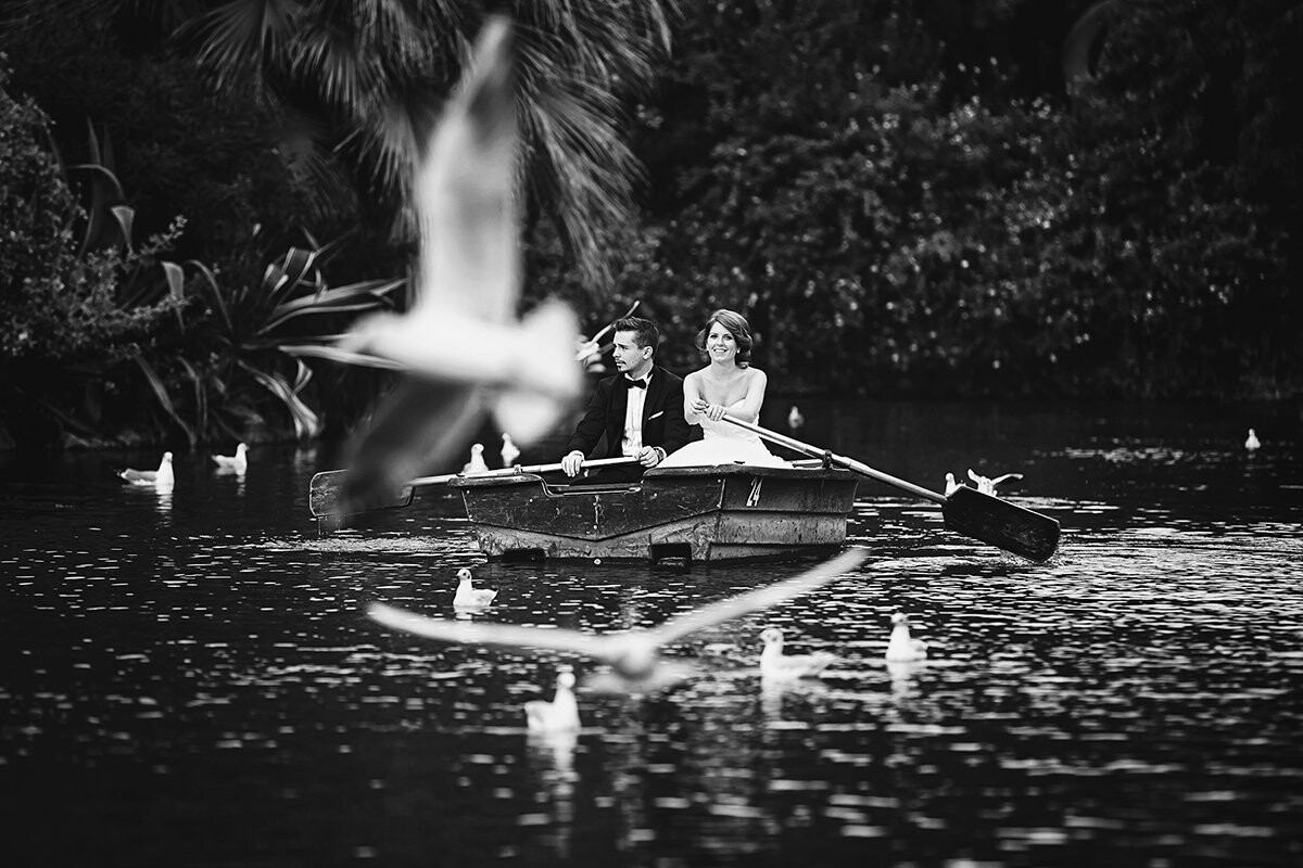 This photo of this lovely bride & groom was taken at the small lake located at Parc de la Ciutadella in Barcelona.<br />
The idea (additionally hoping for the luck to turn out with kind of framing shot like this) came as I saw the big bunch of chilling seagulls and taking notice that they mainly take off towards the embankment I decided to shoot from. So the couple was careful rowing towards the chilling seagulls from behind to only scare them up by present. And big luck it perfectly worked out first try. We had the chance to capture many heartwarming, storytelling and for sure photos with their stories behind the scenes to ad some deserved portraitshots to their wedding story/reportage. Barcelona is such a nice place.