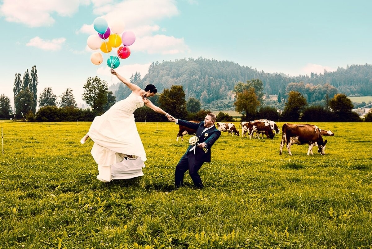 The couple was very close to nature and when I saw this typical Swiss meadow with the cows, I had the picture in mind. I grabbed my stepladder and we went in the middle of the field. The idea was that the groom rescues the bride who flies from the balloons thereof. On this set we just laughed.
