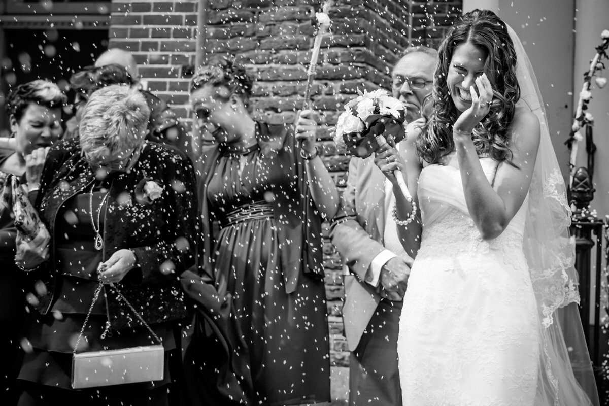 I love the tradition of throwing rice after a wedding ceremony. Unfortunately it is forbidden in a lot of places in the Netherlands. Most of the times people are blowing bubbles or toss rose petals. So having the opportunity to photograph people throwing rice is very rare. That's why I really love this picture, where bride Xenia and some of the wedding guests are literally pelted with rice.