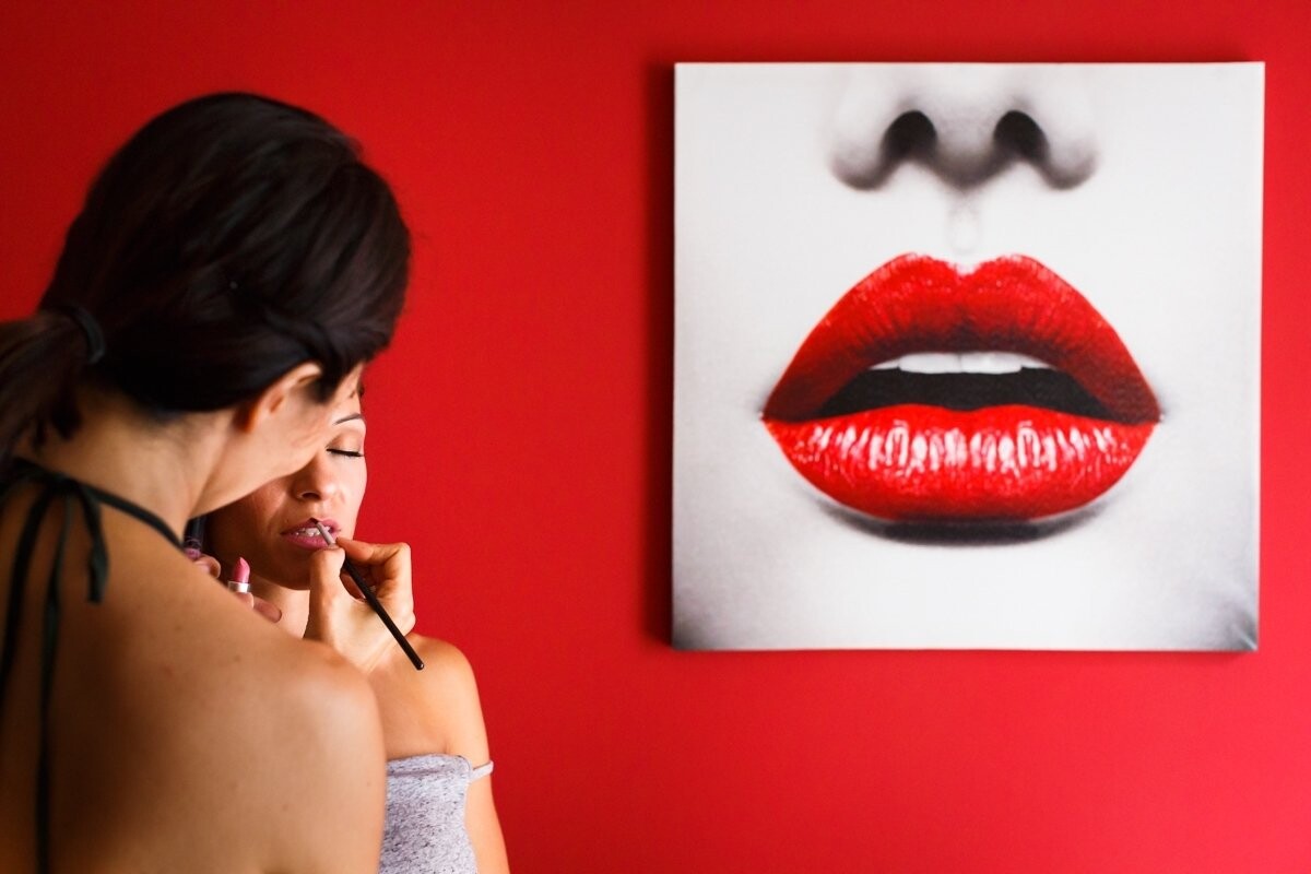 I took this photograph on the Makeup session of the bride. When we got home and saw the photograph of the lips on the wall I knew I had to find the time that the lips could paint the bride to make this photo. What I like most is the color, the red room and  the red lips  that I think makes the picture work better.