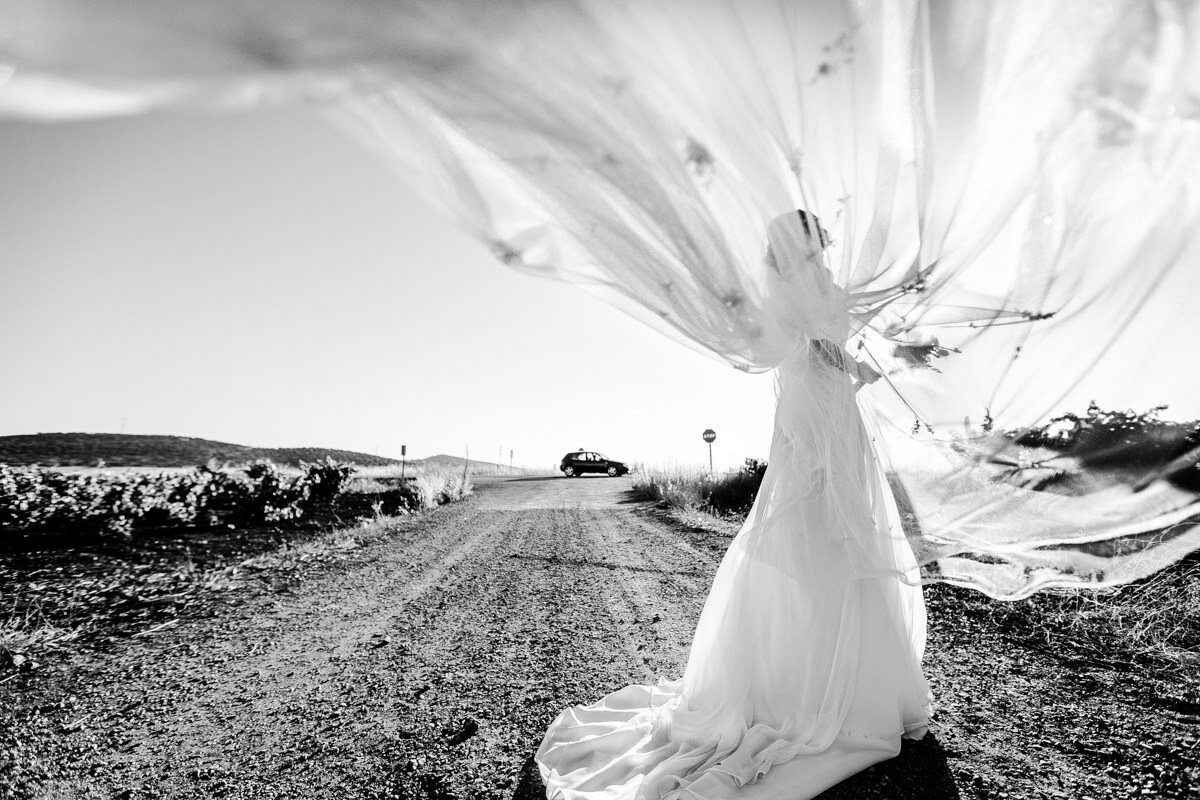 We took this photograph in a village south of Spain, we were doing several tests and finally chose this because I felt that the time had enough strength, at the right time when the veil covered the face of the bride and also just pass a car at that moment. I think the photo without the car would lose interest.
