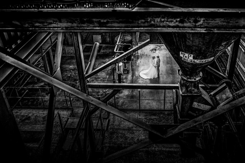 This wedding was near Den Bosch, a city in the south of the Netherlands. Before the romantic ceremony at Castle Heeswijk Dinther, we took the wedding couple Elise en Vincent for a urbex wedding shot in the old factory (de Koekbouw) in Veghel. This old factory scene is an awesome location for shooting wedding and after I was upstairs the couple took a quick romantic look at each other and I shot this beautiful wedding photo just between the old steel constructions.