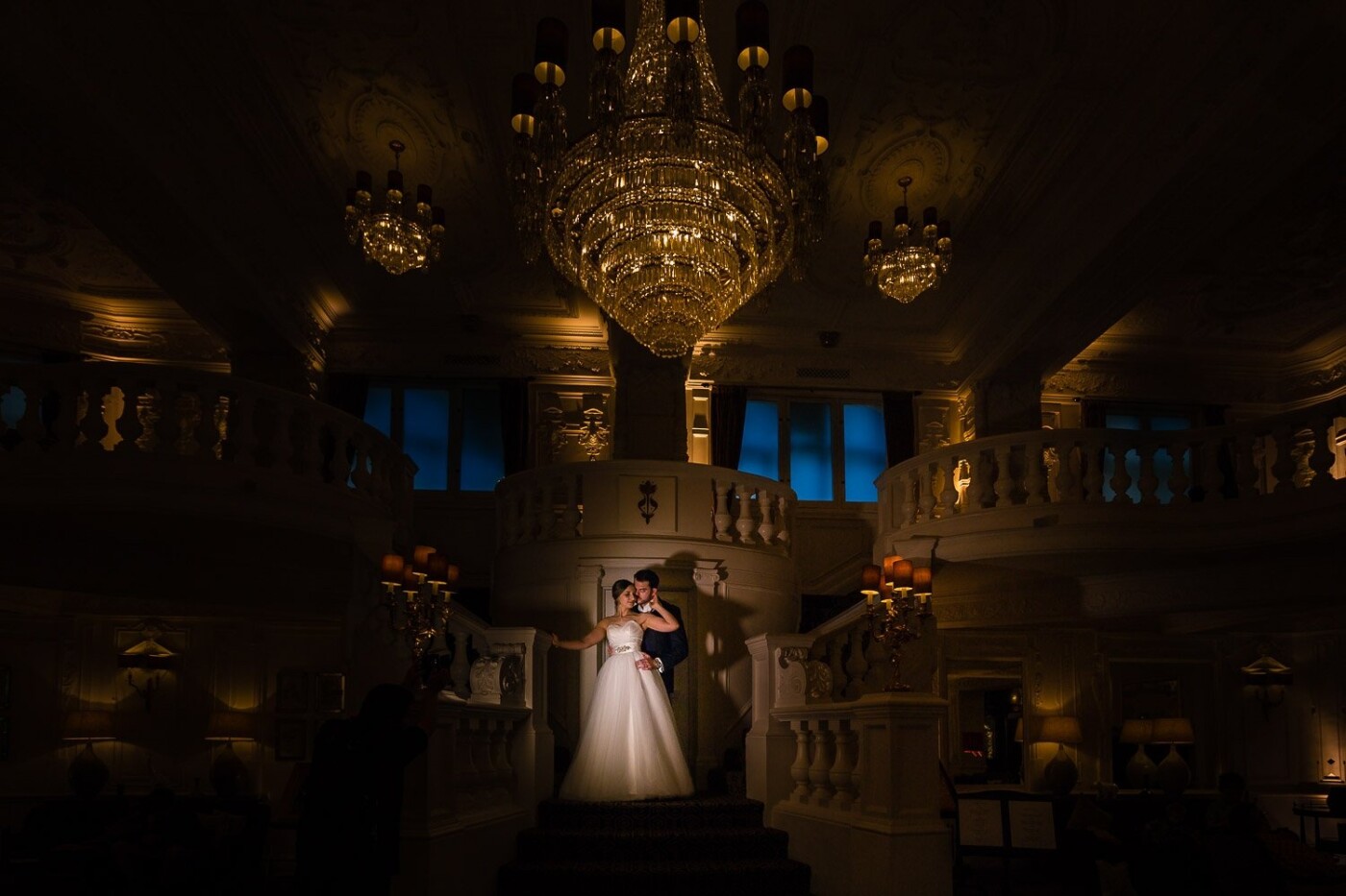 Nina and Matt got married at the stunning St Ermin's in Westminster, London.  One of the reasons they chose the hotel was because of its beautifully ornate rooms.  They knew they wanted a photo on the sweeping staircase in the hotel lobby but I wanted to create something dramatic for them befitting of the opulence of the hotel.  I would normally take a shot like this towards the end of the night but Nina was rushed into the hospital only a few days before the wedding for major surgery and, understandably it was looking like she might not have the energy to stay that late.  So in the late afternoon as the guests were taking their seats for the wedding breakfast we took a little time out to create this shot.  I exposed for the chandelier and the various lights in the lobby and used a video light to highlight the couple.  Thankfully the couple is as delighted with the image as I am.