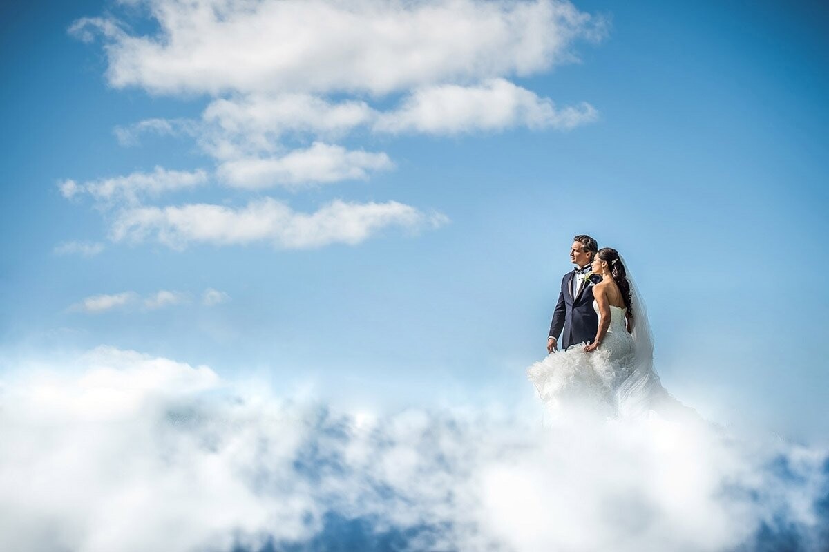 At the couple's engagement session, we took shots of them with the stars and the moon. On the wedding day, it was only suiting to take them to the clouds! During their portrait session after the ceremony, we took them to hills on this beautiful day. This image was made in camera using the reflections on the iPhone. When our couple saw the image, they exclaimed "you took us to the clouds!