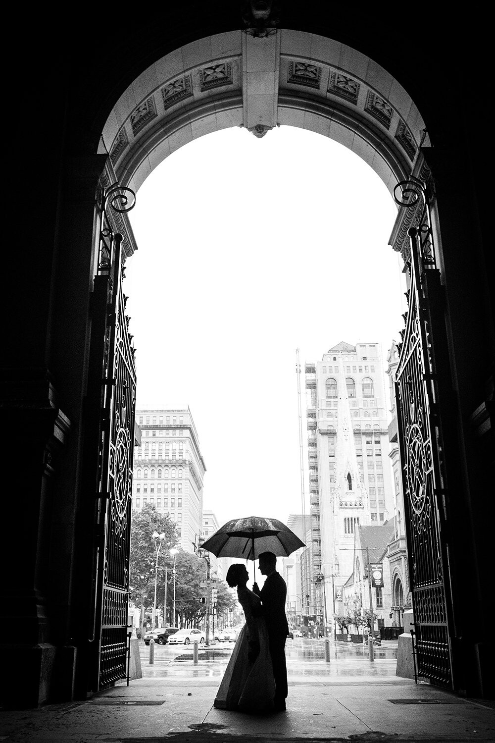 The rain was falling hard during this particular wedding. Luckily we planned to shoot around Philadelphia City Hall which is one of the most incredible masonry buildings in the world. As we were shooting it started to rain really hard so we jumped into one of the tunnels there. Seeing the light, I asked them to just hang out at the opening of the tunnel at which point the groom made a joke causing his bride to bend backwards in just the perfect way, making their silhouettes a really intriguing capture when I pressed the shutter.
