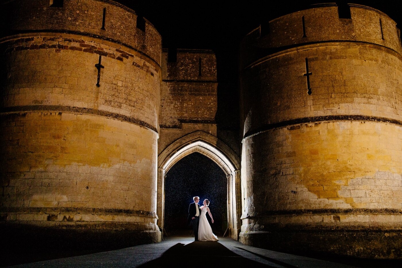 This was one of the very last images I took on the wedding day of Lauren & Charlie which took place at the fabulous venue of Rockingham Castle in Northamptonshire. I’d planned to do an evening shot like this once I’d arrived and seen this impressive entrance into the venue. We’d had glorious weather all day and just as night fell it started to rain - which with the backlighting has added something a little bit extra to the image.