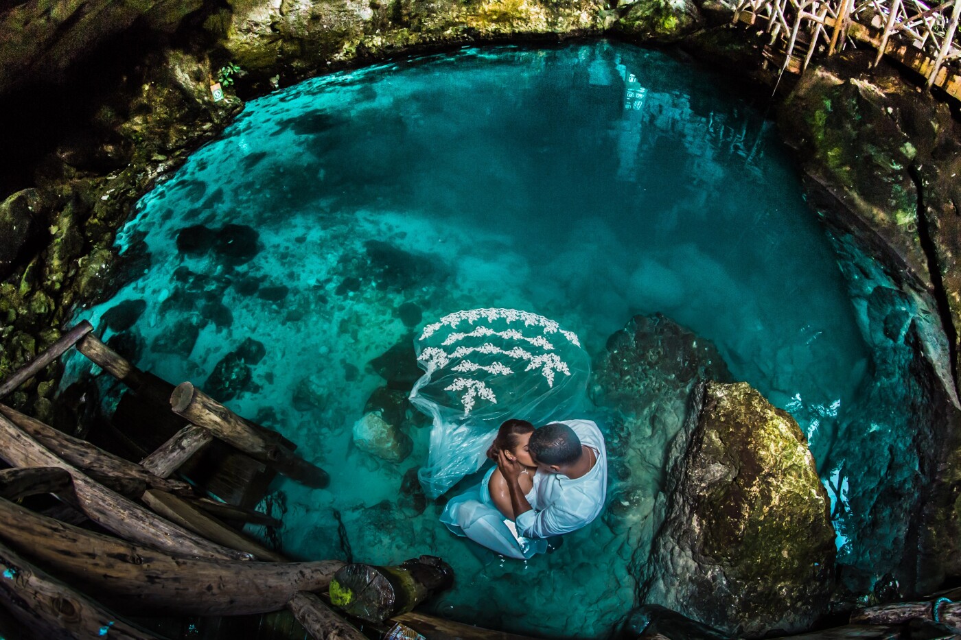 This image was taken in Hoyo Azul, Cap Cana, Higuey, East of the Dominican Republic. Catherine and Joaquin were married in November of 2015 but they wanted us to do “the trash the dress” and an adventurous photo shoot. We met the same day of the photo shoot. However, Catherine and I had spoken a lot over social media. The day of the photo shoot it was very cloudy and it rained. Cap Cana is a spectacular place and even though it was raining, we caught some amazing images. Joaquin was not very convinced about jumping in the water but as soon as he saw me jumping in with no problem, they both entered the water and had fun taking the images for this beautiful “trash the dress”.