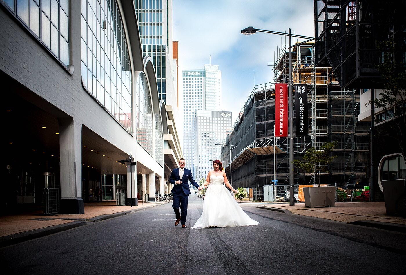 This couple are typical Rotterdam citizens and wanted their wedding pictures a little industrial and city like on their weddingday in October.<br />
<br />
We had to wait minutes and minutes untill the street was fully empty (it's a crowdy place in Rotterdam city with lots of traffic).<br />
<br />
The Dutch photomuseum is also situated in this street and the banner of the museum is visible in red on the picture which i thought was a funny accent as the theme of this couple was red for their special day. The black banner says (it's in Dutch)  "gives ideas some space"  which i thought was a nice combination mentioning this photo ;)<br />
<br />
