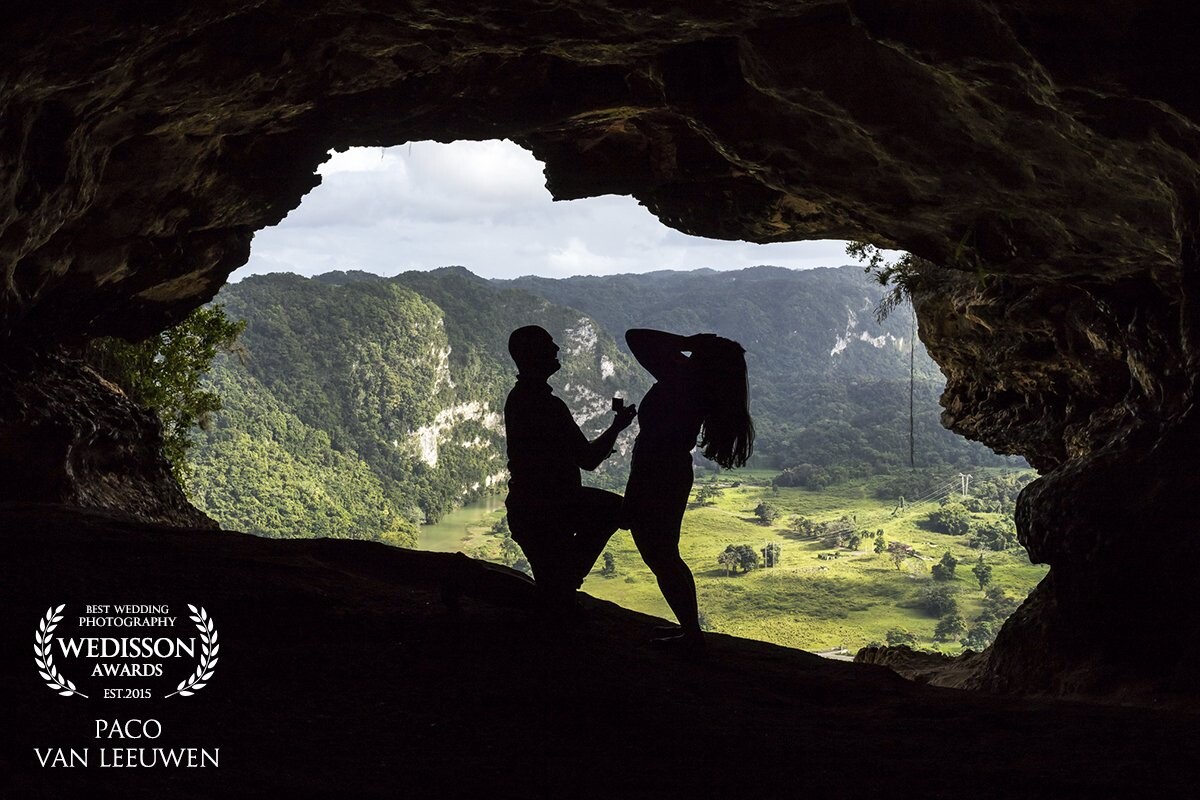 A proposal in Cueva de la Ventana in Puerto Rico. To be more precise, my own proposal! :)<br />
<br />
When ever we go on a holiday together, we always that a couple of epic shots for our selves at wonderful locations. Only now I had other plans then just a picture. My girlfriend is from Puerto Rico and she is very proud of the Island and the culture.<br />
<br />
I had been planning this for months, getting the ring, looking up locations and of course practicing what I was going to say. I couldn't wait to ask her, so I made sure we went on a road trip to visit a few places but this was the one where I wanted to propose to her.<br />
<br />
Unfortunately we had to take a tour seeing the caves. This meant that we were with about 50 people and that made me worry about the shot I had in mind. At the end of the tour was the cave. Of course everyone wanted pictures at the edge, so I had some time to set up a tripod, with remote. That way I could snap the shot at the right time. <br />
<br />
This was set up in a few minutes and then it seemed to take hours before everyone else go their shots. The guid was already addressing people to go back. He offered to take our picture but I nicely declined and told him we would take it when everyone was behind the camera and then we would follow. (I think he kinda knew what was going to happen) He then started telling people to leave and that was the moment. <br />
<br />
I grabbed the ring box and head over to her by the edge of the window. We snapped a few shots, my heart was racing. I dropped to one knee and asked her if she wanted to marry me. Her reaction was, "Oh my god" (and she threw her typical surprise pose as you see in the picture) "YES!!" I got up, kissed her, put the ring on her finger and the whole group started clapping! 