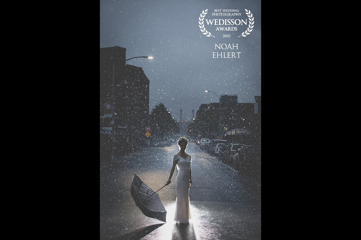 Being able to have opportunities like this  as a photographer is incredible. All the pieces must come together. A beauty of a storm brewing in Brooklyn NY at the same time myself and the bride make our way to an ice cream parlor. The place she wanted to wait while the guests arrived at the venue.  We had done a few photos in a light sprinkle then took cover as it really started to come down. As a photographers, myself and my wife are always up for anything. Pouring rain, blizzard, you name it. On wedding days, you always must be aware of peoples comfort levels. So we sat out the rain for a minute. I said I really didn't want to get her soaked before the ceremony. We sat for about 60 seconds before Meredith asked if I would distract her a bit while she waited. She didn't mind getting wet. No Problem! Photos in the downpour it was. Moving the umbrella to one side for a bit more fearlessness. I recently found out her mother commissioned an artist to do an oil rendition of this photo. This was something special.