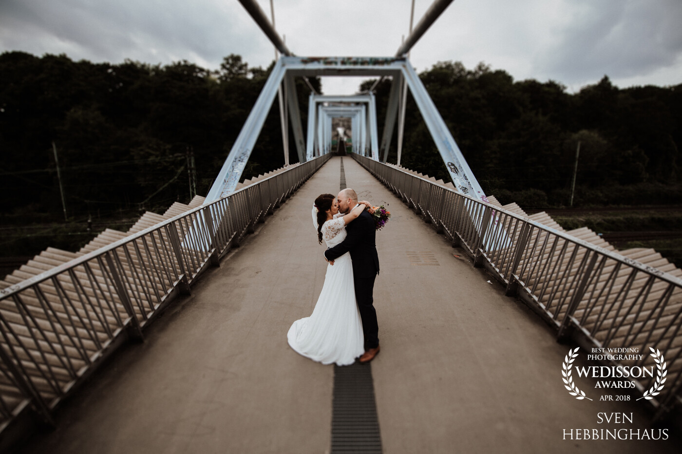 I took this picture on a small bridge during an urban wedding in Cologne. I like this "kiss on a bridge" because the bridal couple was so emotional and sweet. I capture this moment with this beautiful structure of the bridge.