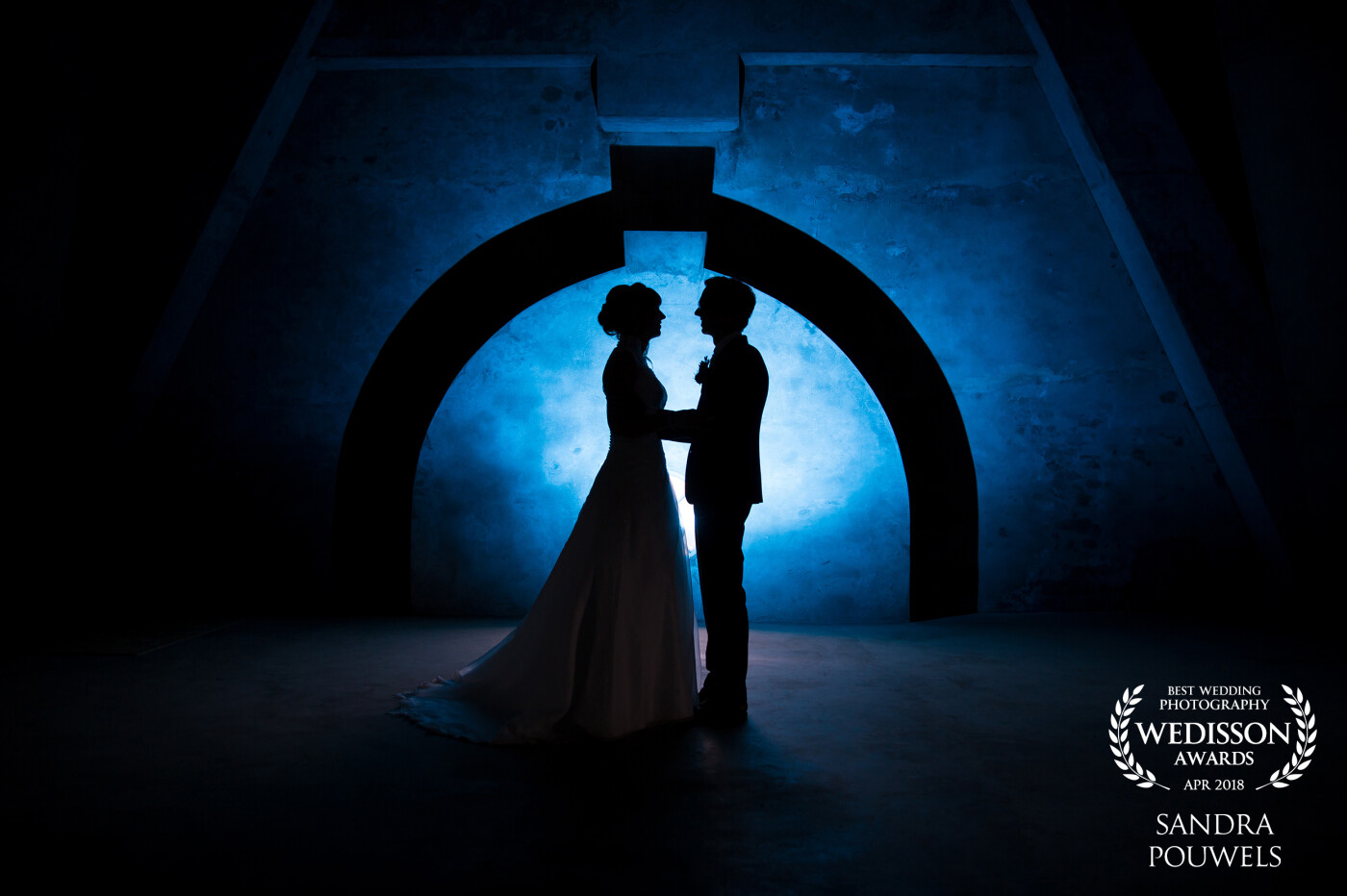 On a rainy day this picture was taken in an old water tower. By pointing a blue flash on the wall we created a beautiful silhouette of the bride and groom. 