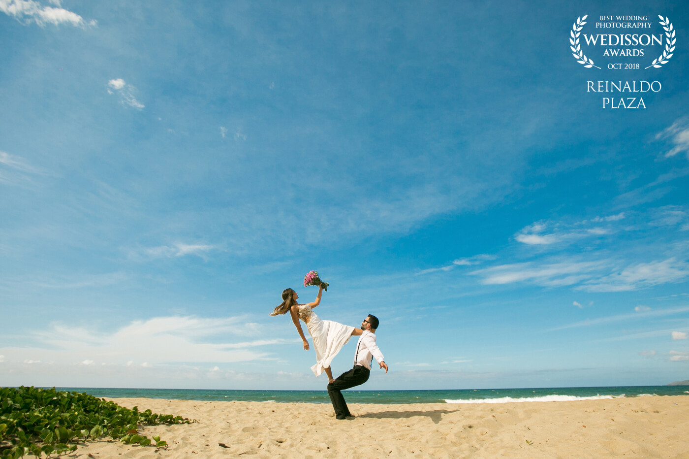 This photo was taken in La Sabana Beach in Venezuela, we where waiting for the sun to go a bit down but we want to make some photos in that time, when the bride says "i have an idea for a photo" then she start climbing her husband and make that pose for this picture.