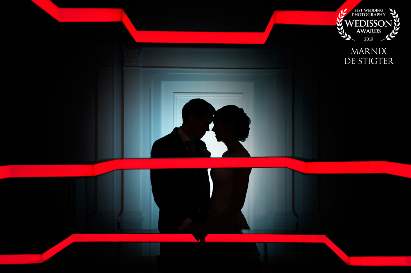 This wedding location had a crazy lighting structure on the second floor. I felt it was best to make use of their silhouettes and light up the background to have it complement the red strips of light. 