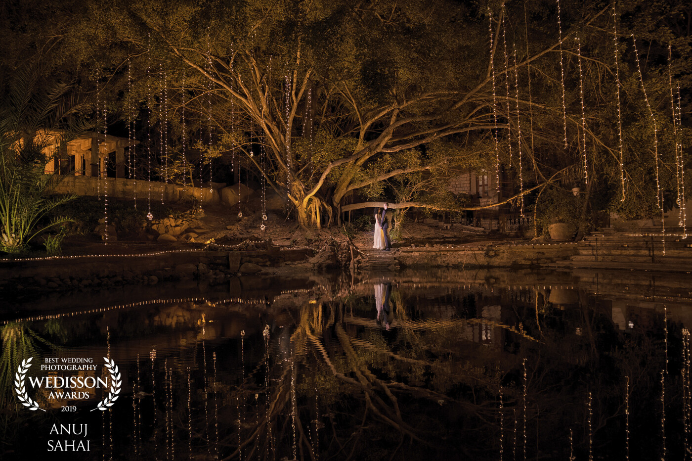 This shot was taken at the cocktail party post wedding. The venue had a natural pond under a huge banyan tree. I could see a clear reflection of the tree! I thought why not use natural reflection and get a great shot! The tree is also adding more beauty to the shot!
