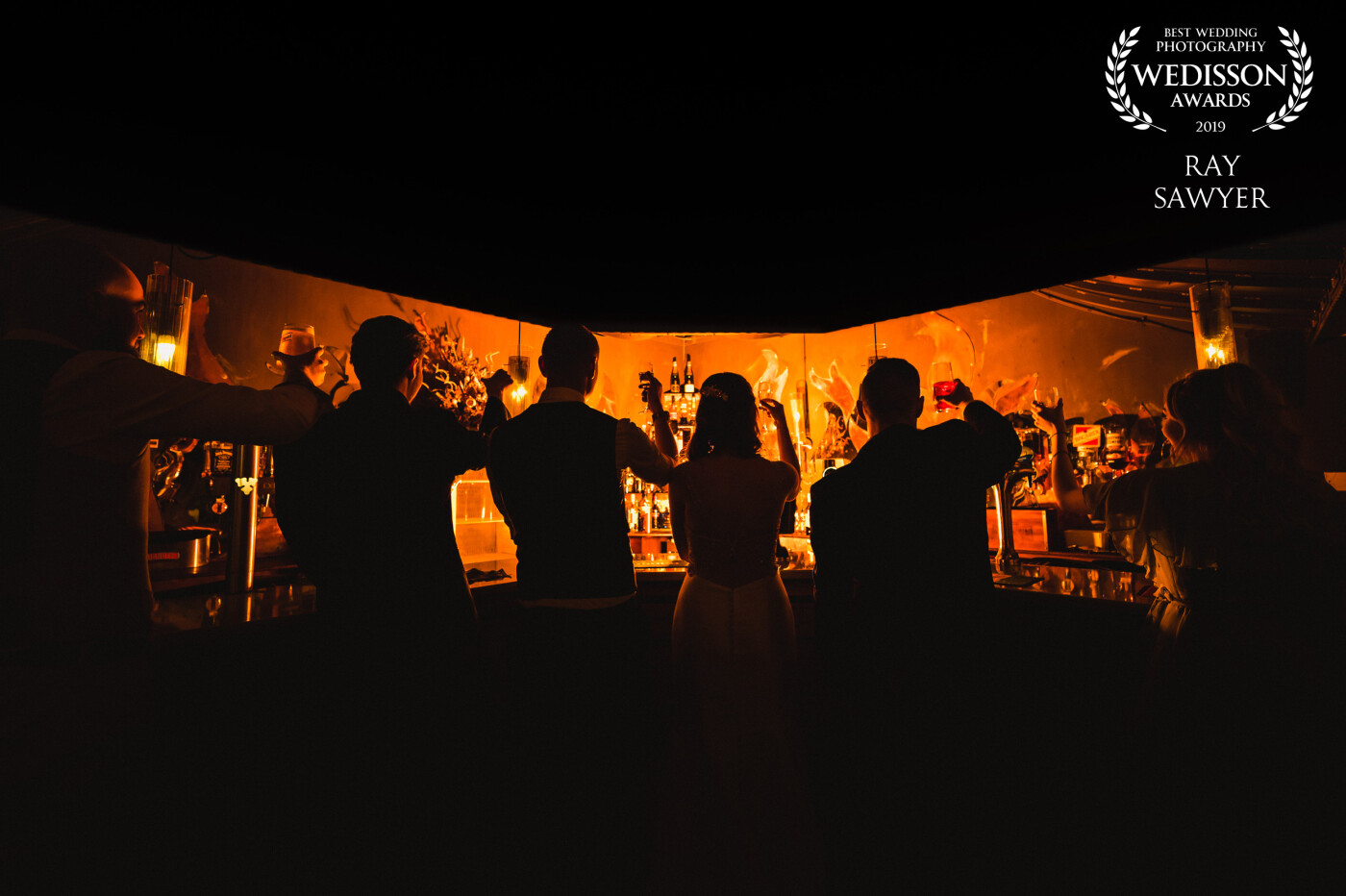 The bar at the hotel had an interesting shape so I added some full CTO gels to my flash and created a silhouette shot of the bridegroom and friends raising a glass to happiness.
