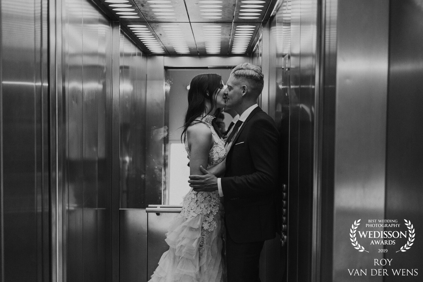 A black and white photo of a wedding couple in an elevator in Haarlem, The Netherlands. The location was called; deDAKKAS. Shot by Roy van der Wens Wedding Photographer and Videographer from the Netherlands