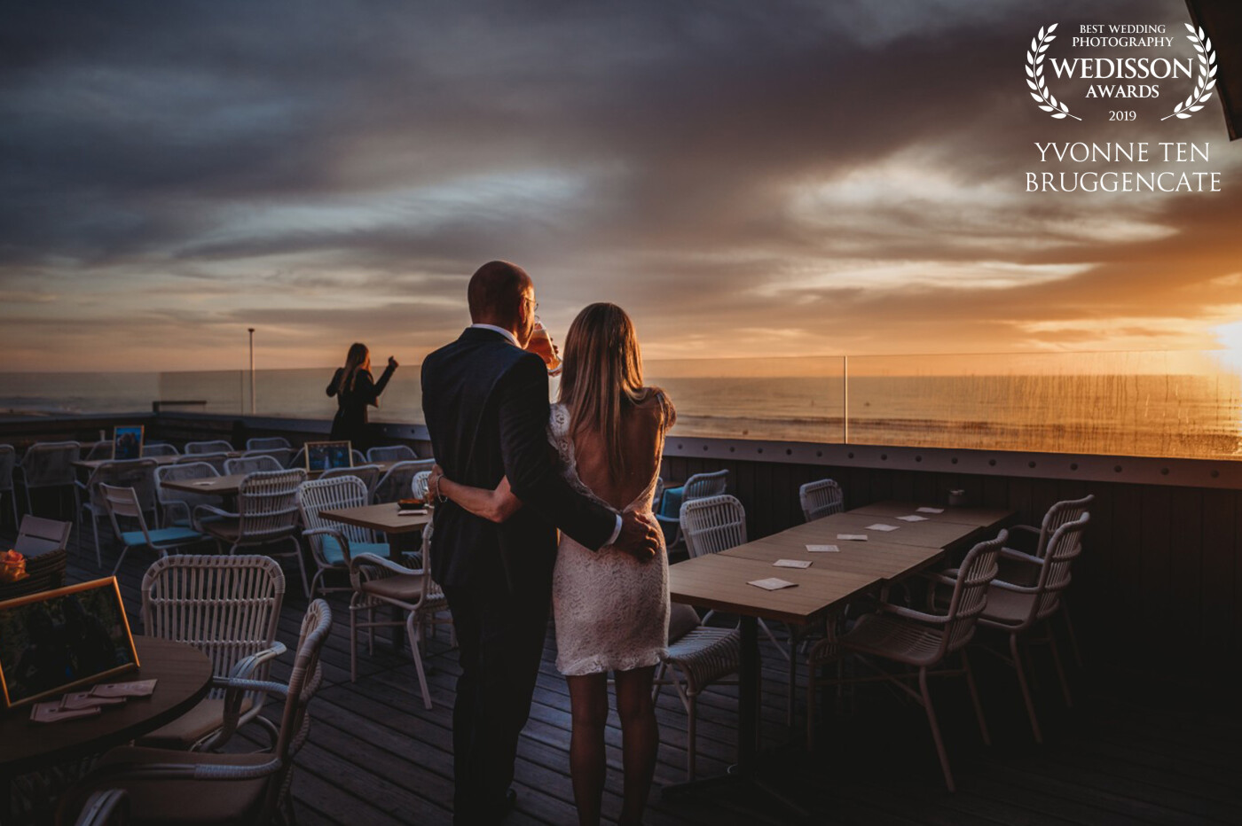 These two lovebirds got married in Canada. When home in Holland, they booked a lovely after wedding shoot on the Beach to celebrate their love. At this moment they are waiting for their guests to arrive, watching the most beautiful sunset. Their daughter is in the background 