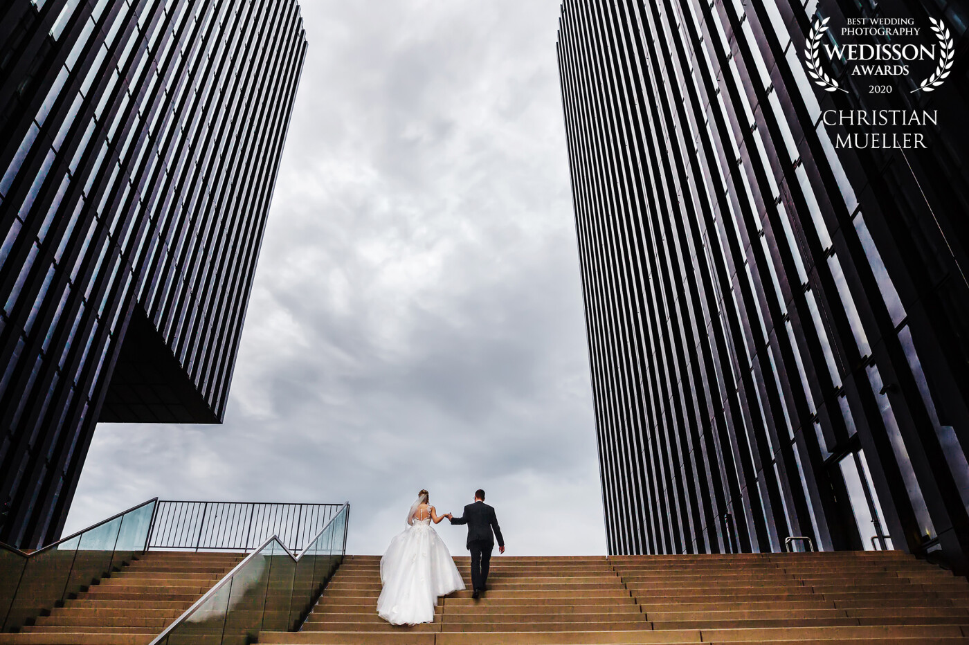 It was rainy and cloudy on their wedding day, but I love the mood with the dramatic clouds in this picture. And the urban look of the high rises give a good frame for the couple. <br />
The picture was made at the Medienhafen in Düsseldorf, Germany.