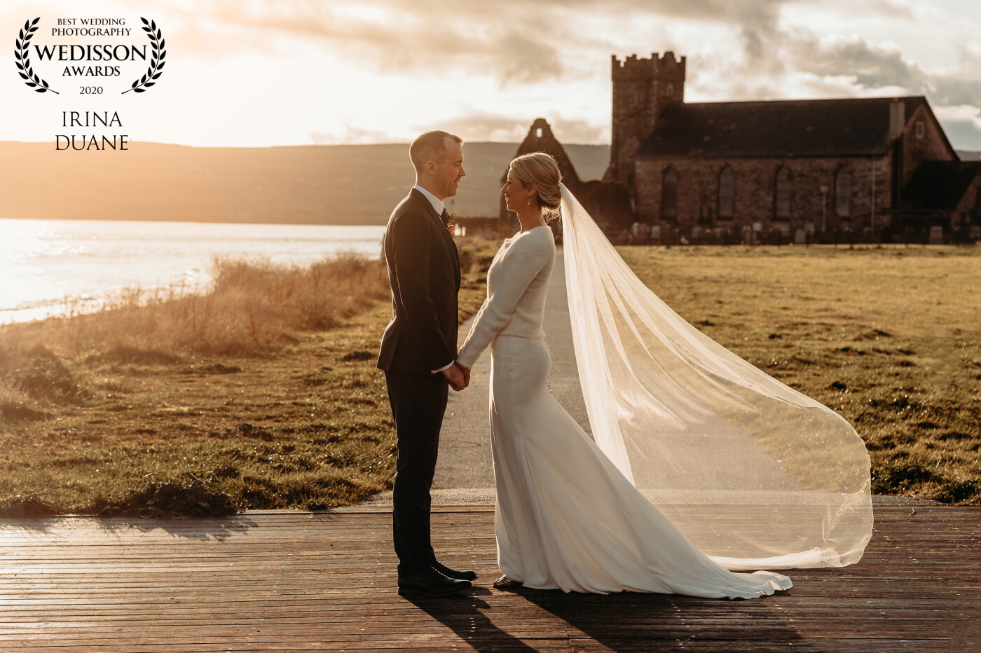 This photograph of Clodagh & Barry was captured in a beautiful winter sun in Dungarvan, co. Waterford. Ireland. The ruin of the old church behind them is known locally as the ‘clogchas’. It was founded c.1290. The surviving buildings consist of the 13th-century chancel and the 15th-century tower.  The soft light makes it seem like a fairy tale. 