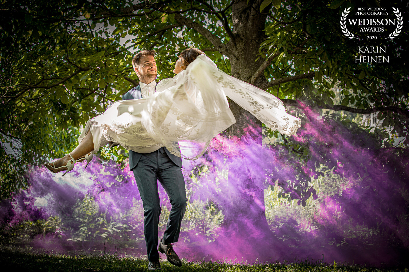 It's amazing how you can play with the sun and your camera. In June 2020 we went with a couple to a beautiful place in the Netherlands. On a field with some trees we tried out smoking bombs as the light beams between the trees were so nice. While the wedding couple was rehearsing their wedding dance, we shot this image of them, with a purple haze on the back. We're so font of matching different things together. In this case: nature/love with art colors/smoke.