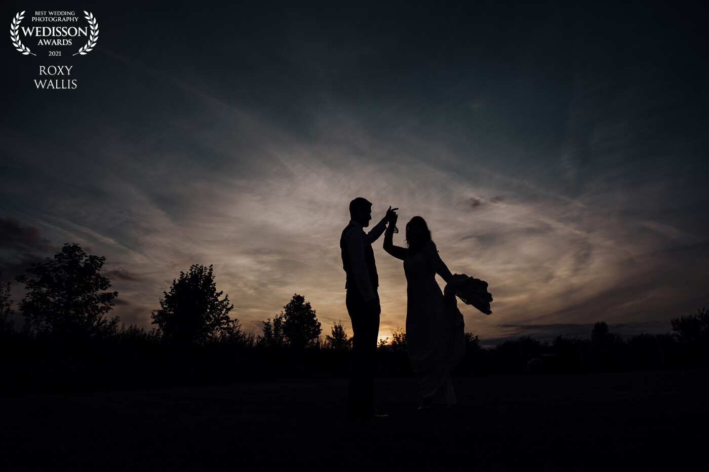 The skies may have started off cloudy at this wedding but the evening rewarded us with this glowing and dramatic sunset. <br />
I managed to capture some twirls in front of the setting sun to add some interest and movement to their silhouette.