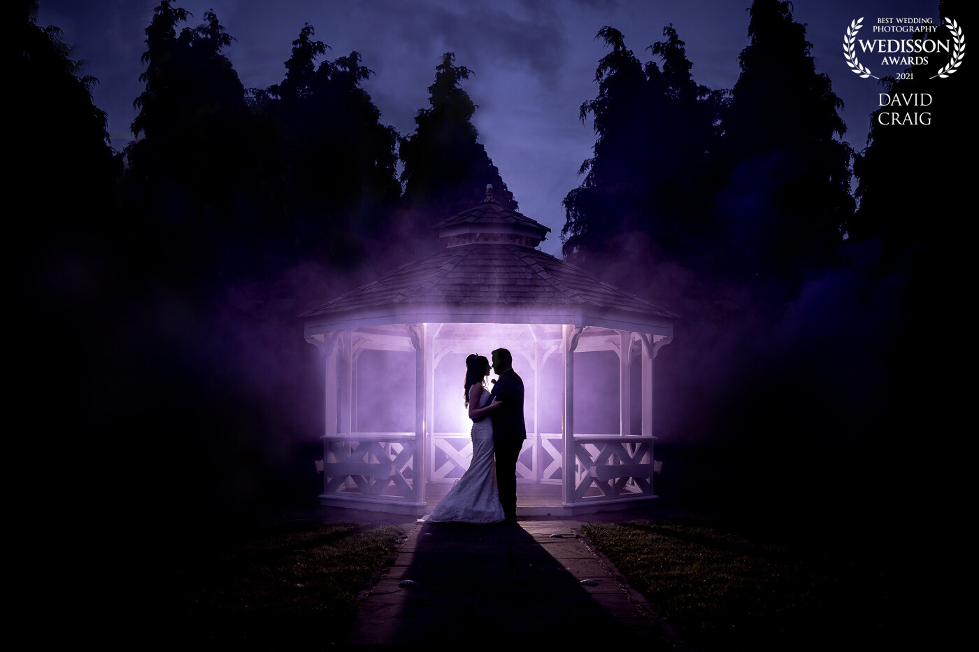 Simple but effective shot. Used a purple smoke bomb with an AD200 quite far behind the couple. Also had a light set up on the front for different versions of the same pose, but wasn't activated on this shot as I wanted to go for the silhouette look.