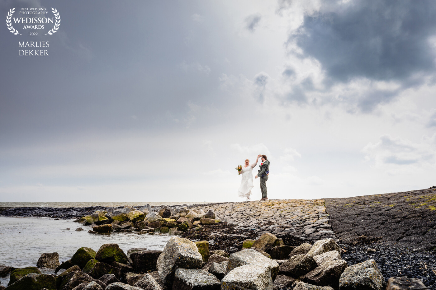 A wedding on Terschelling. My favorite Dutch island, where i am on regular basis. On the south part the island is protected with a dike where we went for this photo. The clouds make it an atmospheric and complete composition. <br />
The couple has this photo in their livingroom now in big format above their lounge suite. So lovely! A bigger compliment you can not get as a photographer i guess.
