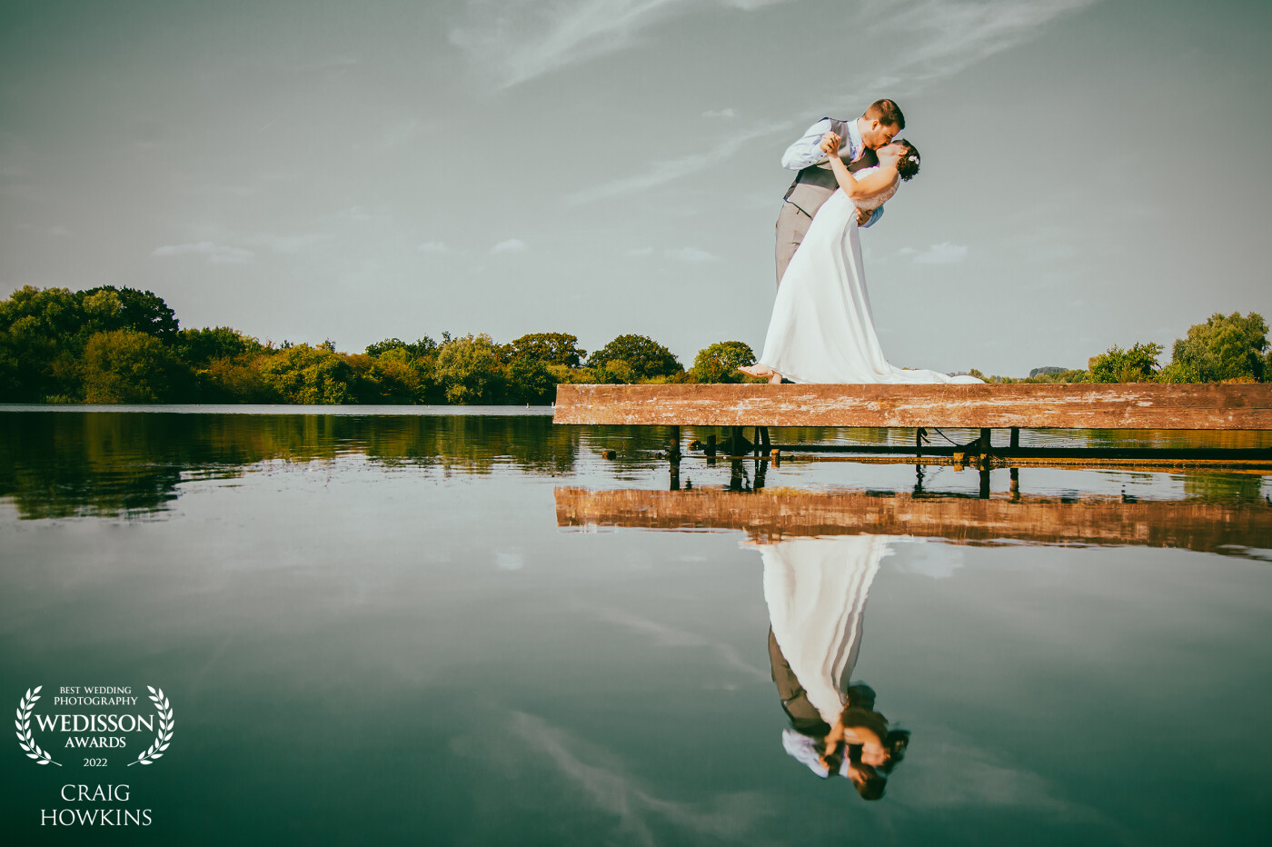 This photo was taken at Grendon Lakes in Northamptonshire. We had the perfect calm water and the bride and groom just embraced each other in this lovely moment which gives the image a hint of the silver screen.