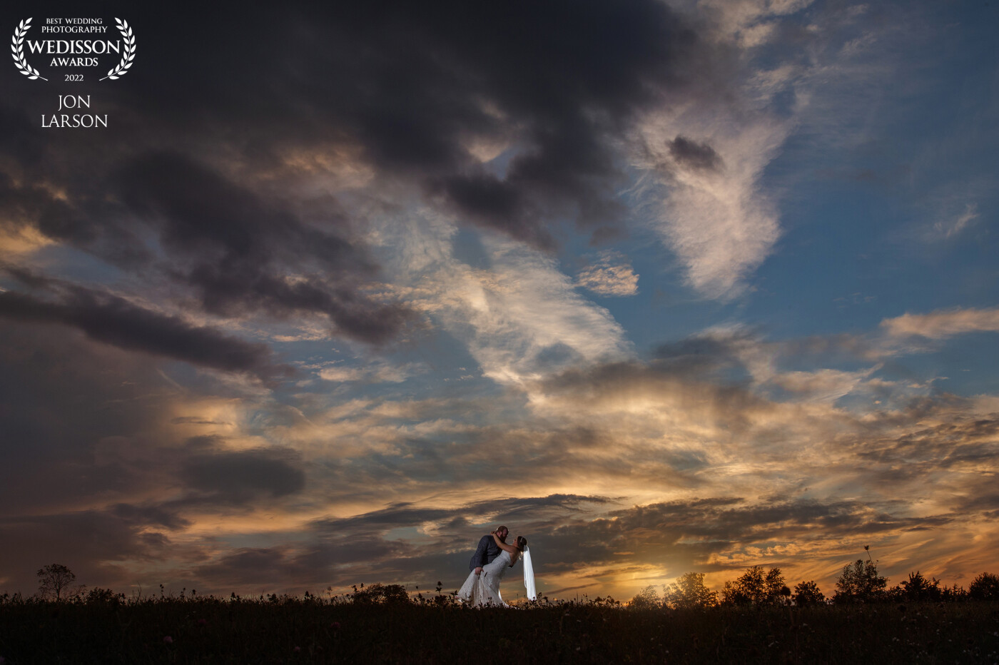This photo was on the country hillside just before the sunset. Noticing the sky, my team and I along with the couple took a walk into this beautiful scene! Being some distance from the newly married couple they just began expressing their love in many ways as I just captured it. laying low to make sure I was able to compose as much sky as I could.
