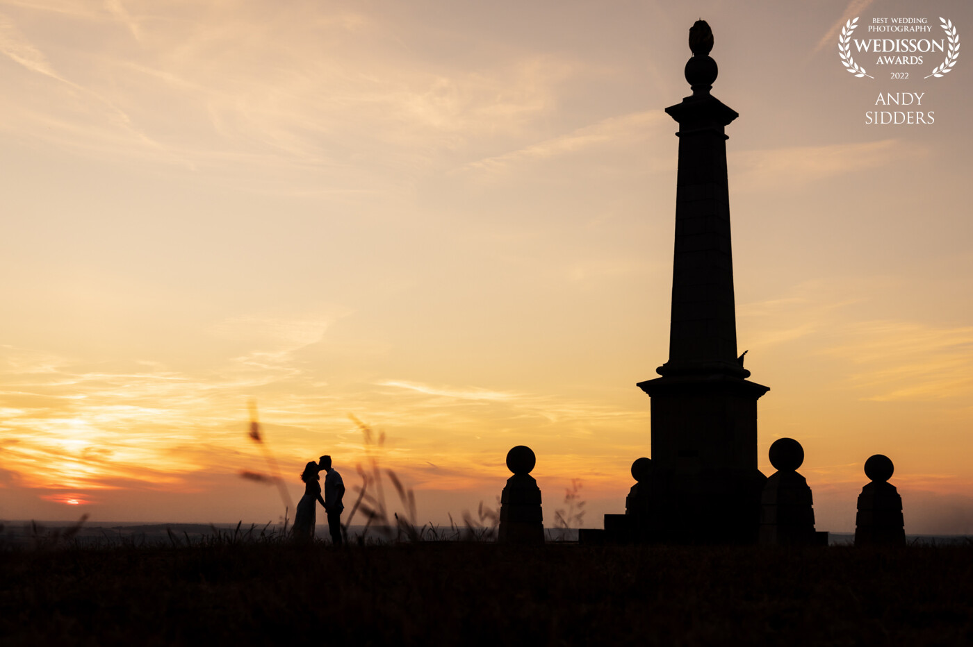 This silhouette was taken on a pre-wedding shoot at Coombe Hill in Buckinghamshire, UK. I lay low on the grass to take the shot and framed the couple between blades of grass in the foreground.