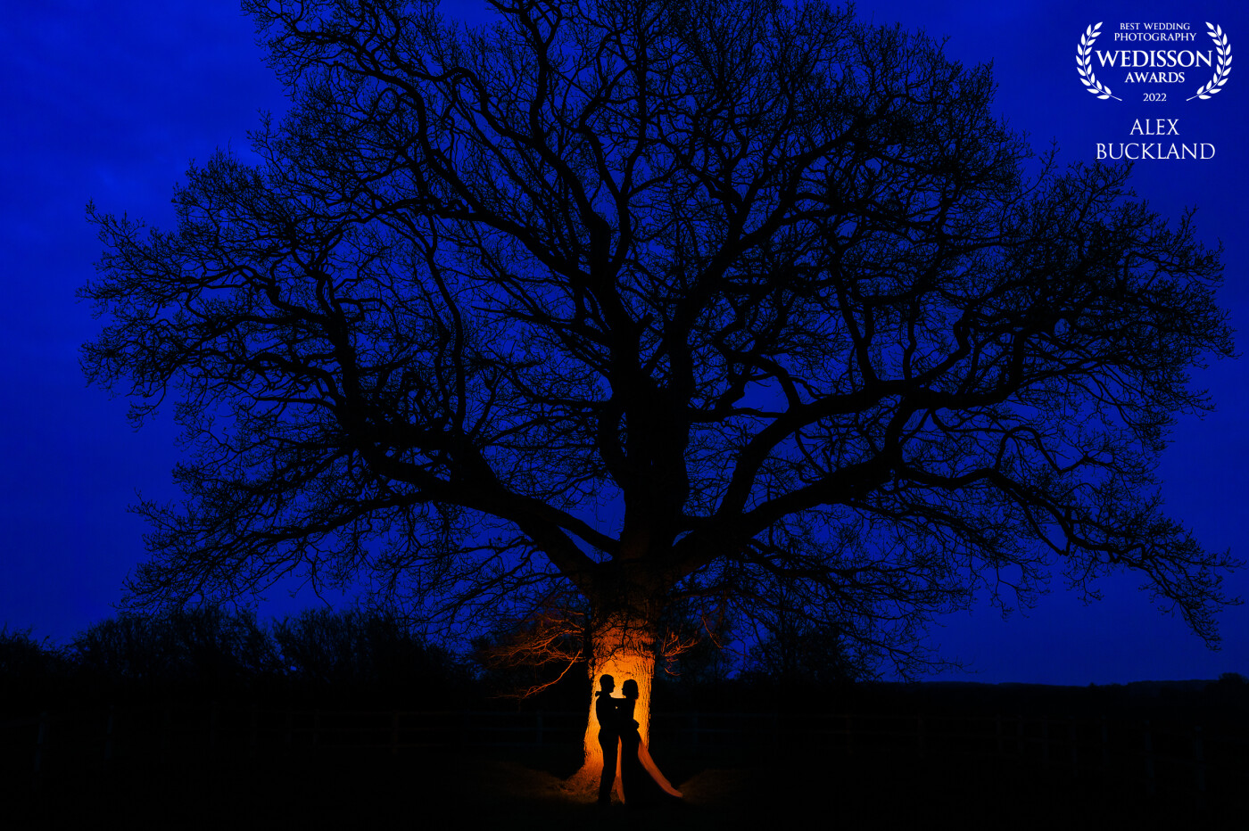 I noticed this incredible tree opposite the venue when I arrived and knew I had to incorporate it somehow later in the day for a creative twilight photo! I asked the couple to stand close to one another in front of the tree, I then fired a flash using a full CTO gel towards the tree to silhouette the couple, whilst also reducing the white balance to enhance the blue hour of the sky!