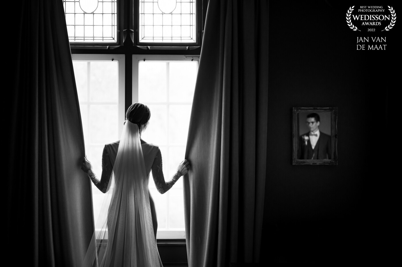 The couple had some spare time between their reception and dinner so I took them to a room with large windows I spotted during the day. The windows had long curtains and there was a small mirror on the wall. My first intention was to pose the bride between the curtains and as I was working towards this I noticed the small mirror and placed the groom so I could see him and have him included in the final image.