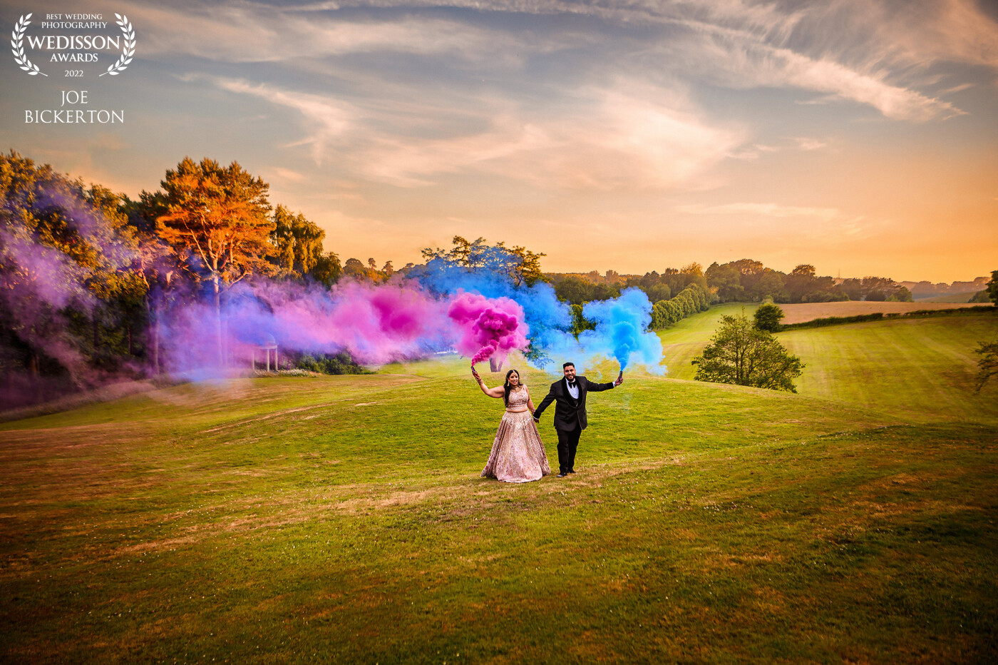 This couple celebrated their English / Indian fusion wedding at Delamere Manor in Cheshire with colourful smoke flares as golden hour started in June 2022.  Rather than shoot tightly, I used a wider 28mm lens to capture the sky and gardens at the Manor which added the the drama of the image!