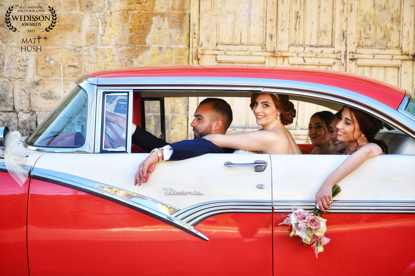 10th June 2022 was Leeann & Luke’s wedding day on the little island of Gozo in the heart of the Mediterranean. I love the lines of the arms of the bride, groom and bridesmaid complimenting the design lines of their friends car. The pastel flowers matching the rustic wooden door was a bonus!