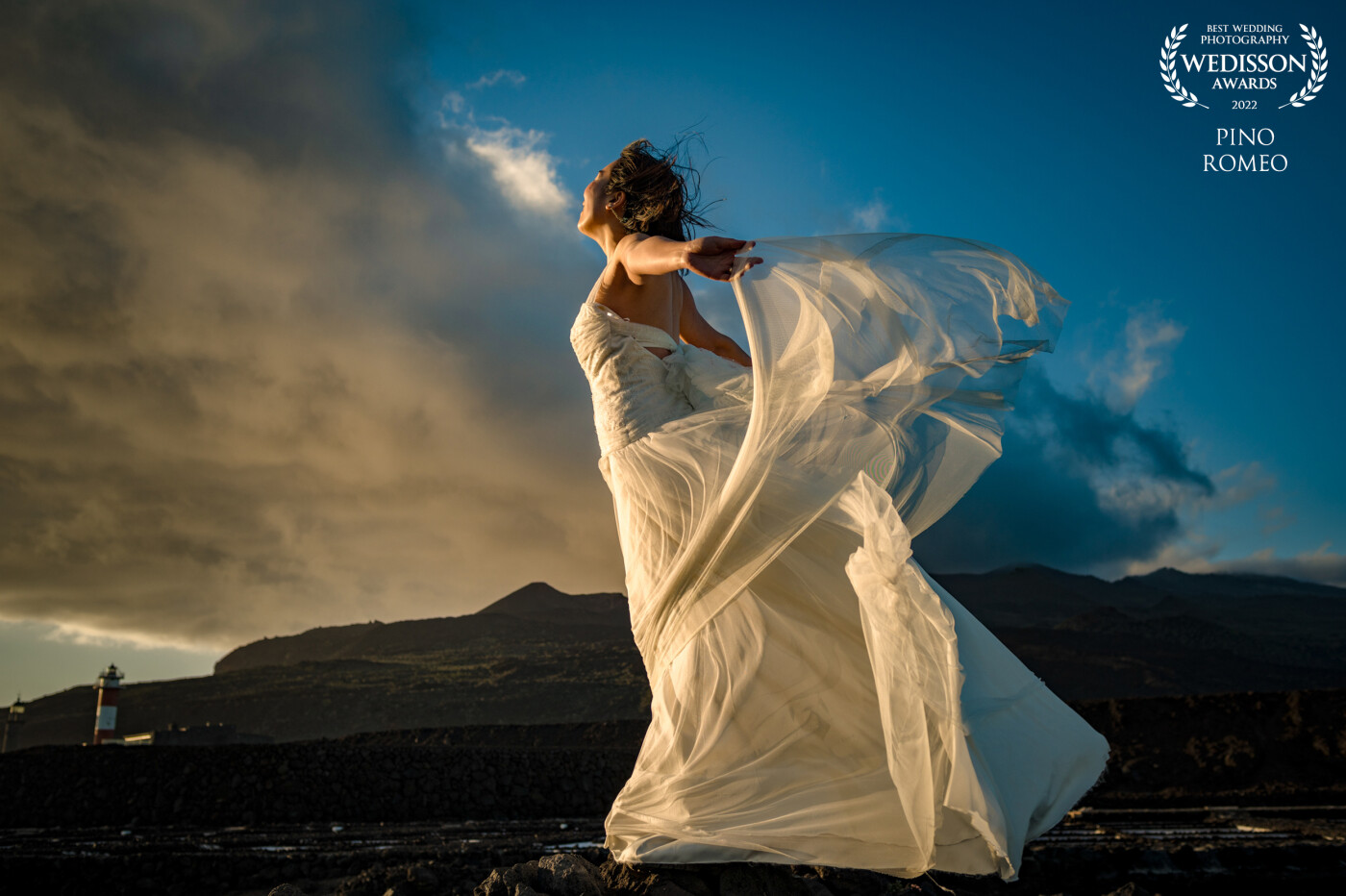 Joan, a young bride, faces the wind and the clouds.  On the island of La Palma in the Canary Islands, the entire south is made up of recent volcanoes and cooled volcanic lava.  The salt pans of Fuencaliente face the Atlantic Ocean, and the wind often blows strongly.   An ideal location for a post wedding portrait session.