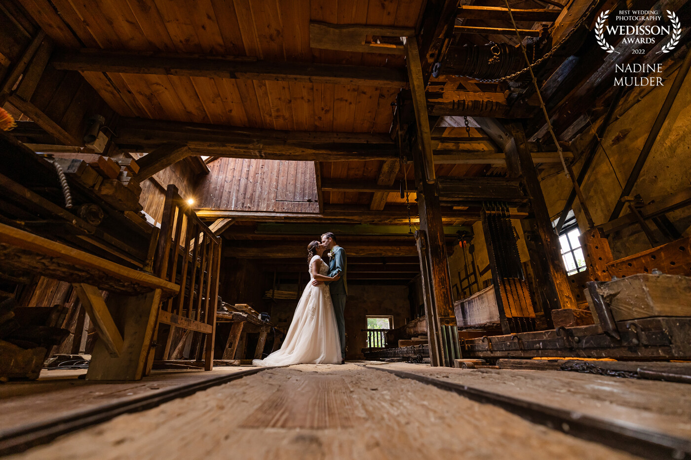 This couple married at an amazing location. After the ceremony everyone moved to the party location. A loud sound of a machine caught my attention and I spotted this location, a beautiful sawmill. I loved the colors and the natural light inside and asked these newlyweds to pose for this picture.