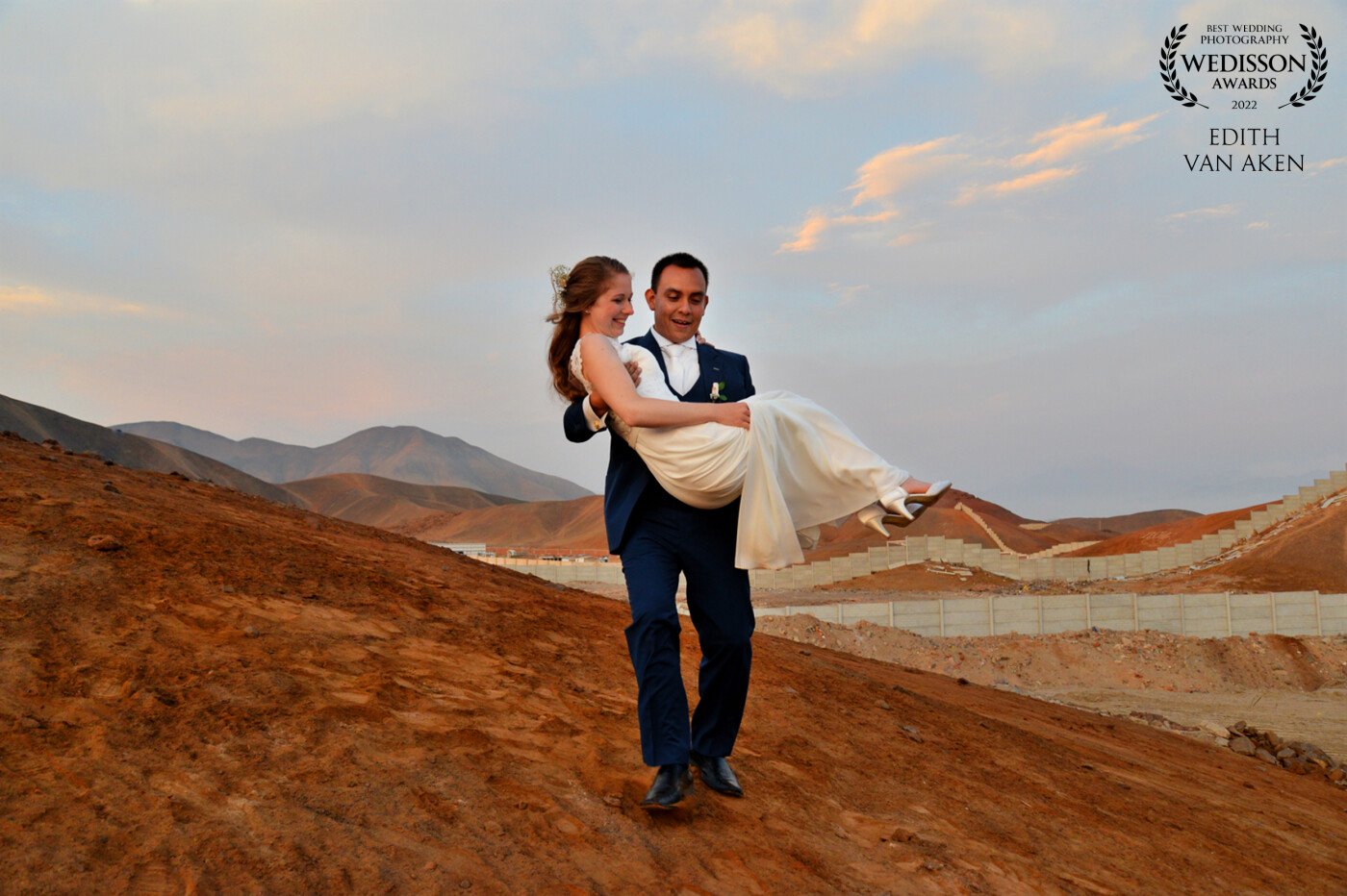 This couple married in the beautiful country Peru. Just a few hours from the big city Lima.<br />
The ceremonie was on a beach and we did a loveshoot in the harbor. <br />
After the ceremonie and reception I suggested to go to the mountains nearby for a golden hour shoot.<br />
The bride worried about the sand getting on her dress, so the groom lifted her up.<br />
That's when I got this wonderful shot!